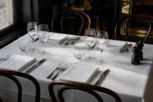 Trois verres alignés de gauche à droite sur une table dressée avec nappe blanche et couverts