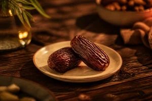 Deux dattes Medjool sur une assiette en céramique beige, éclairage chaud de soirée