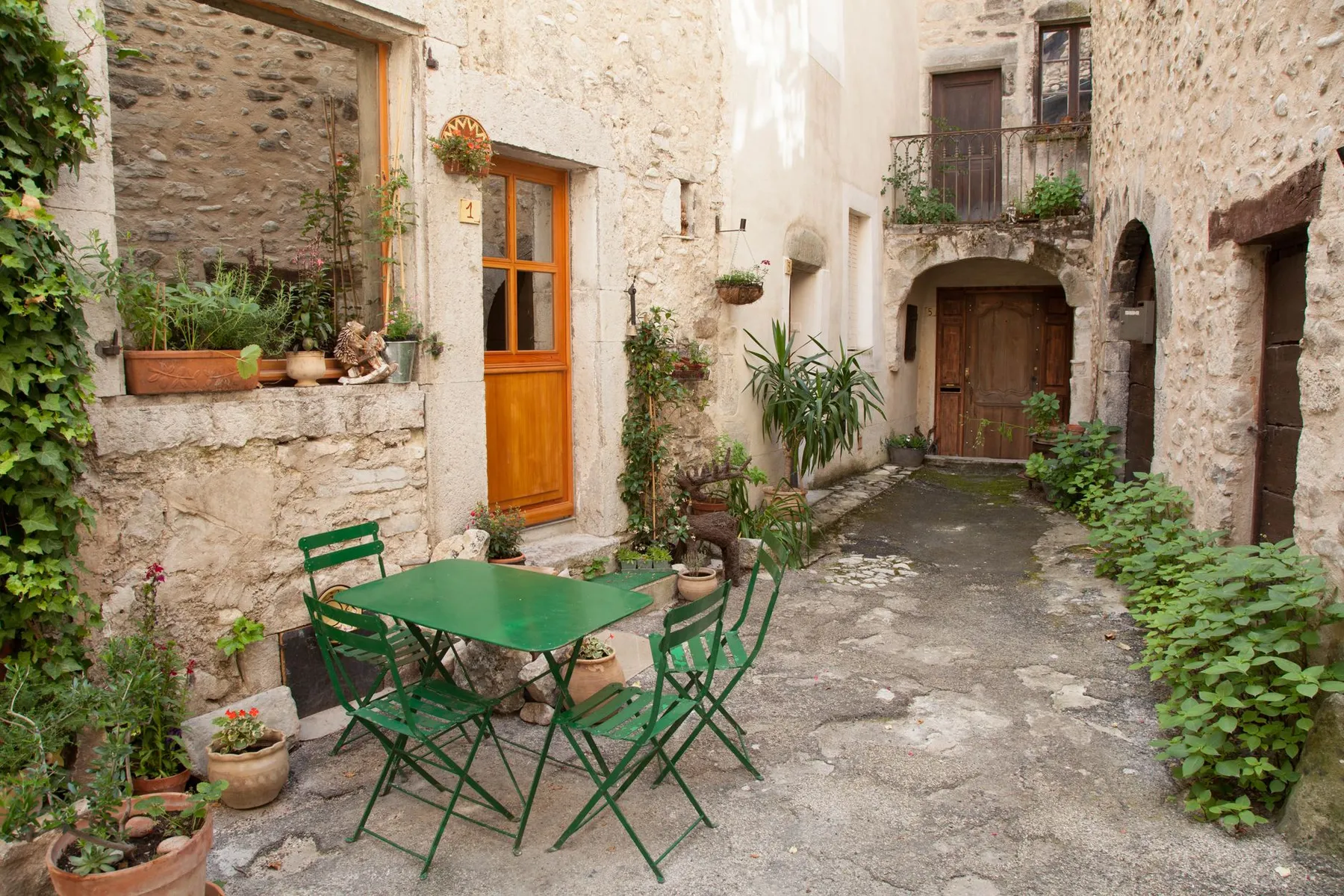 Une table verte dans la cour d'un village de pierre