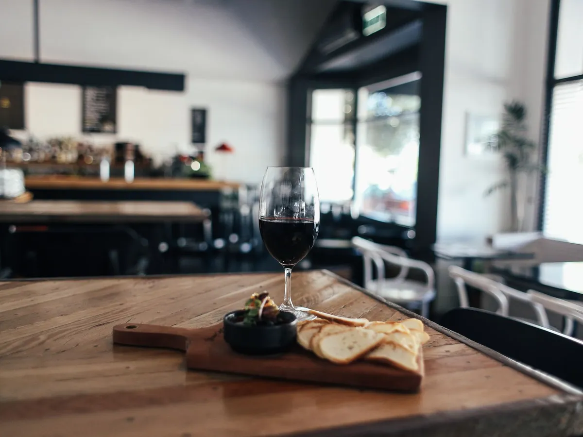 Une planche, un verre de vin et du pain sur une table de cuisine